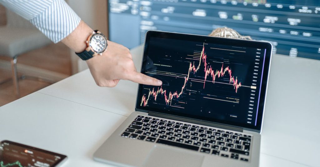 A professional examines financial graphs on a laptop, indicating market trends.